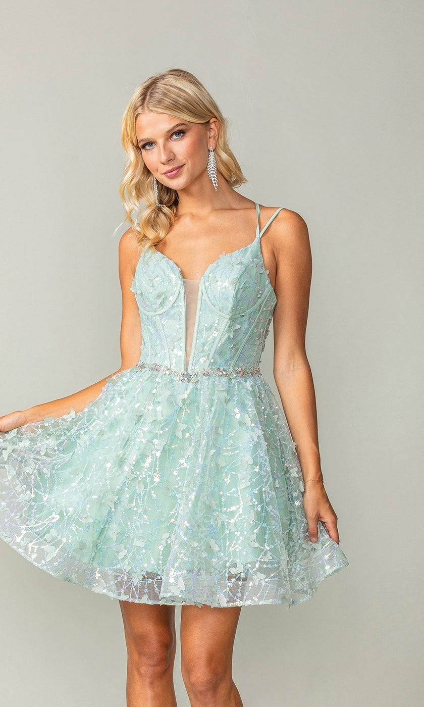 A woman models the Three-D Short Butterfly Homecoming Dress 3350 in light blue, featuring a sheer panel and floral patterns, as she poses against a plain background.